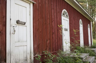 Varjakansaaren vanhan sahakylän ulkohuussi, punavalkoinen puurakennus, monta ovea, ovissa teksti PuuCee.