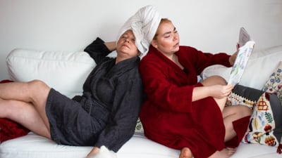 Heidi och Vivi sitter i badrockar i soffan med håret invirade i handdukar.