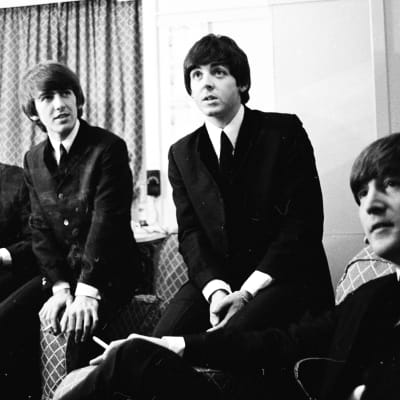 En pressbild på The Beatles klädda i kostymer.
