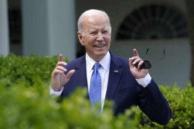 Joe Biden gestikulerar med händerna och ler medan han tittar åt sidan.