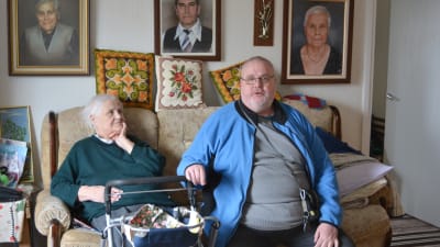 Eila och sonen Ove sitter tillsammans i hennes soffa, Eila har en rollator