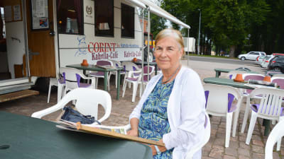 En kvinna som sitter på ett torgcafé.