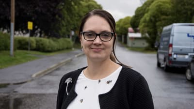 Anna Buss står på en väg och tittar in i kameran och ler in i kameran.