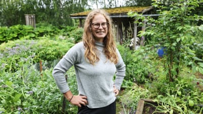 Kvinna står i trädgårdsland.