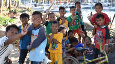 Indonesiska barn poserar för kameran. Många av dem visar olika tecken med fingrarna.