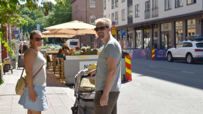 En kvinna och en man står på trottoaren på Kristinegatan. Mellan sig har de en barnvagn. 