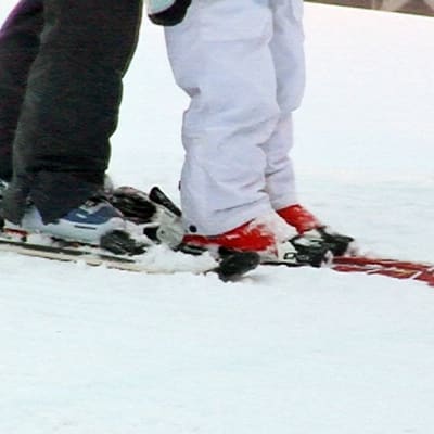 Aikuinen opettaa lasta laskettelemaan.