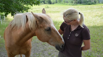 Pia Kulla tillsammans med en häst som buffar på hennes mage.