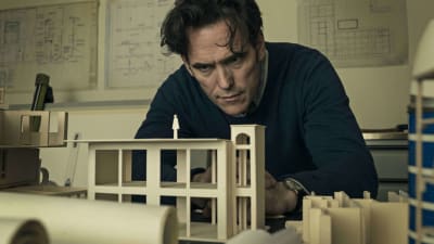 Jack sitter lutad över en miniatyrmodell av en byggnad.