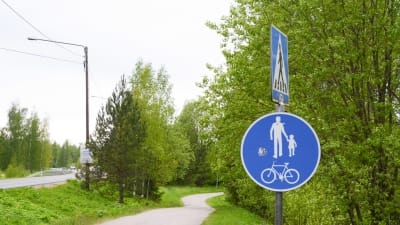 Trafikmärke för gång- och cykelväg framför en gång och cykelväg i en grön miljö. 