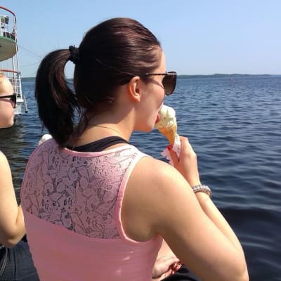Kaksi nuorta naista syö jäätelöä järven rannalla