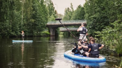 Ett filmteam trängs på en SUP-bräda medan de filmar redaktören Hannamari Hoikkala som står och paddlar på en annan SUP-bräda.