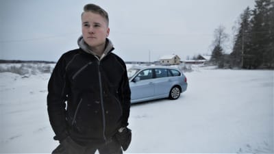 Porträttfoto av Oliver Majors med bil i bakgrunden