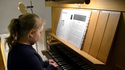 Flicka som spelar på orgel.