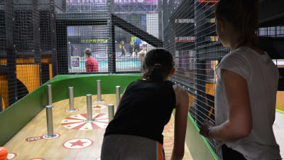 Två personer spelar ett megaflipperspel i ett aktivitetscenter.
