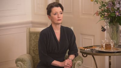 Närbild på Cyril (Leslie Manville) som sitter på en stol och ser bestämd ut.