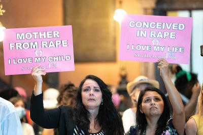 Två demonstranter håller upp skyltar under en abortdemonstration.