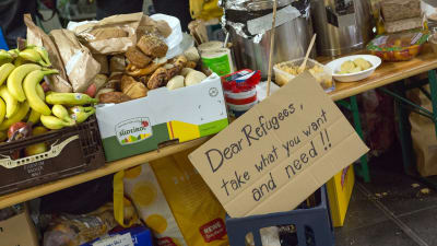 Ett bord med mat på, samt en lapp där det står "kära flyktingar, ta vad ni vill ha och vad ni behöver".