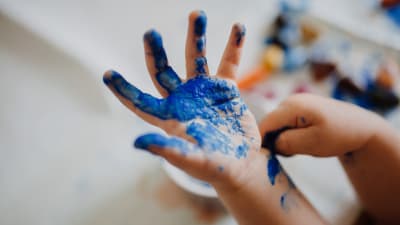 en liten glad hand som färgats blå av fingerfärg