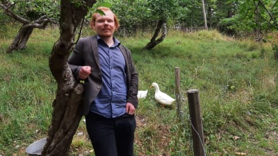Man bredvid ett träd. Ankor i bakgrunden.