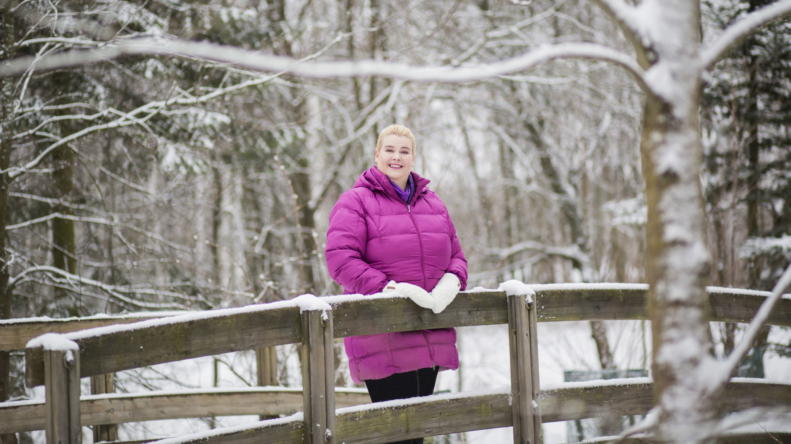 Nainen värikkäässä takissa talvisessa maisemassa.