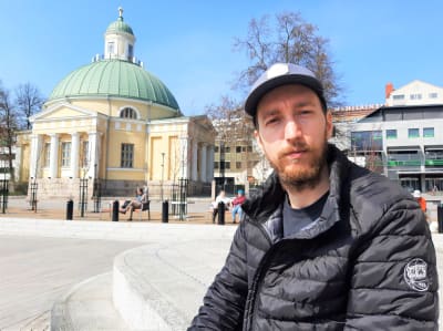 En man sitter på en bänk på Salutorget i Åbo. 