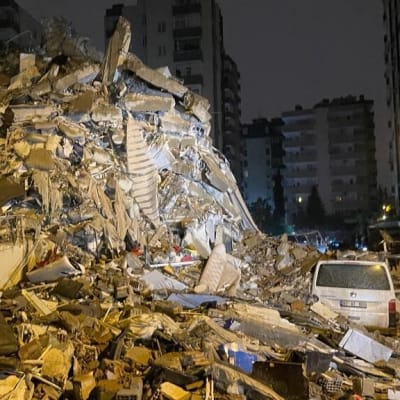 En vit skåpbild bland en massiv hög av bråte av en byggnad som rasat.