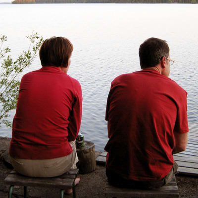 Nainen ja mies istuvat järven rannalla.