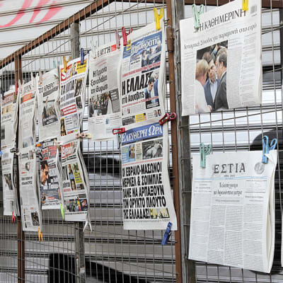 Kreikkalaiset tutkivat sanomalehtien kansia Ateenassa.