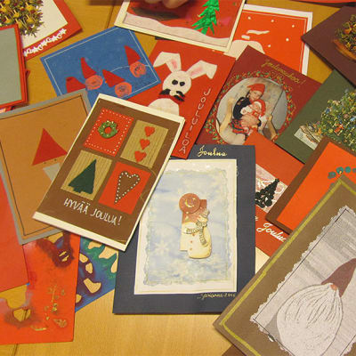 Sari Pokelan askartelemia joulukortteja pöydällä, aiheina muun muassa enkeleitä, tonttuja ja  pupuja. 