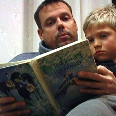 Pappa Johan Lindberg och pojken Adrian Lindberg sitter tillsammans och läser