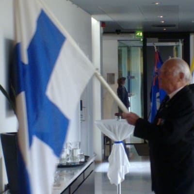 Sotaveteraani Kurt Antskog kantoi Suomen lippua Tukholman suurlähetystössä.