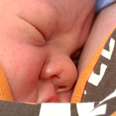 Muutaman päivän ikäinen vauva äidin rintaa vasten.