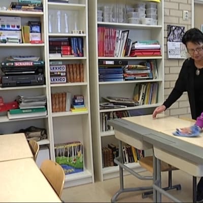 Kiinasta Suomeen muuttanut Shu-Ling Wang siivoaa koulun pulpettia.