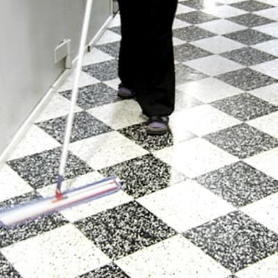 Nainen siivoaa käytävän lattiaa.