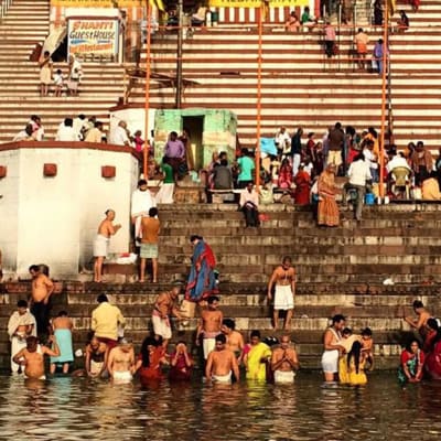 Ihmiset kylpevät Gagnesissa, Varanasin kaupungissa.  Ihmisiä on myös taustalla näkyvilla portailla.