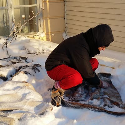 Tuija Isopahkala näyttää, kuinka vaatteita hierotaan lumella.