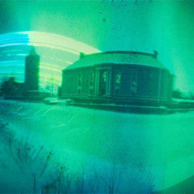 Vihreän ja harmaan eri sävyissa oleva kuva, jossa ovat  Kokkolan vanha vesitorni ja Vartiolinna.
