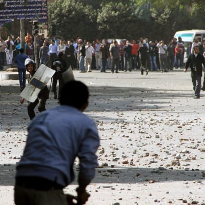 Egyptiläiset mielenosoittajat heittelevät kivillä mellakkapoliiseja Tahririn aukiolla Kairossa. 