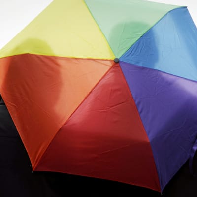 Samaa sukupuolta oleva pari seisoo yhteisen sateenvarjon alla helsingissä.