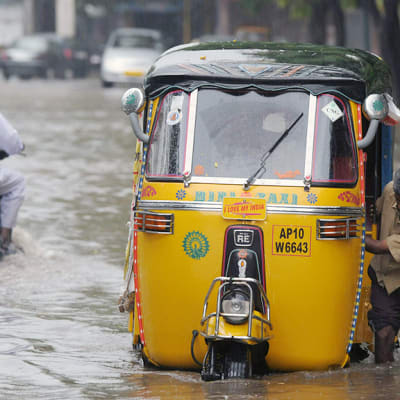 Intialainen riksakuski työntää kulkuvälinettänsä rankkasateen aiheuttamassa tulvavedessä Hyderabadissa.