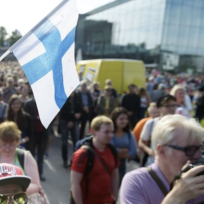 Mire Ibrahim heiluttaa Suomen lippua monikulttuurisuutta puolustavassa mielenosoituksessa Helsingin Kansalaistorilla.