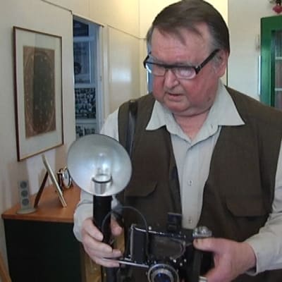 Lehtikuvaaja Antti Suominen tarkastelee vanhaa kameraa.