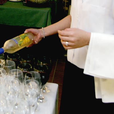 Tarjoilija kaatamassa viiniä laseihin.