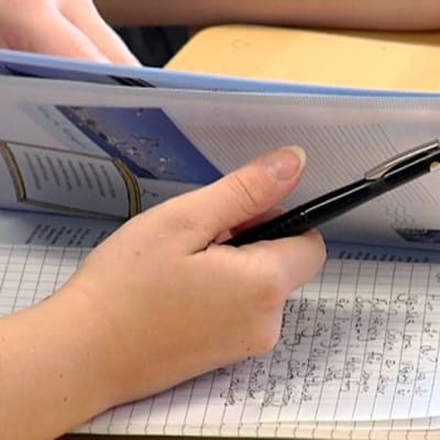 Opiskelija selaa ruotsin oppikirjaa.