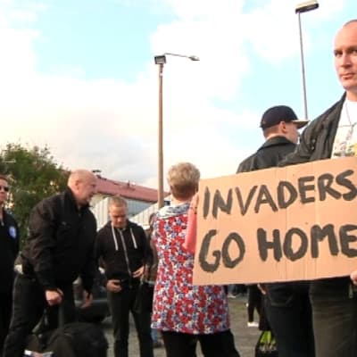 Mielenosoitus Forssassa, miehellä kyltti "Invaders go home"