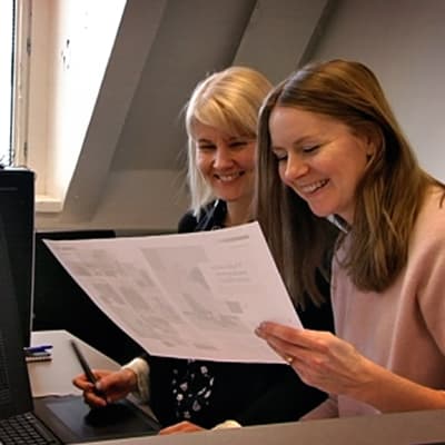 Costumen päätoimittaja Sanna Sierilä katselee A3-kokoista paperileiskaa yhdessä lehden AD:n kanssa.