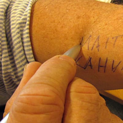 Kuvassa mies kirjoittaa muistivinkkiä käteensä