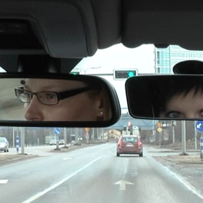 Kaksi naista autossa katsoo peruutuspeileihin.