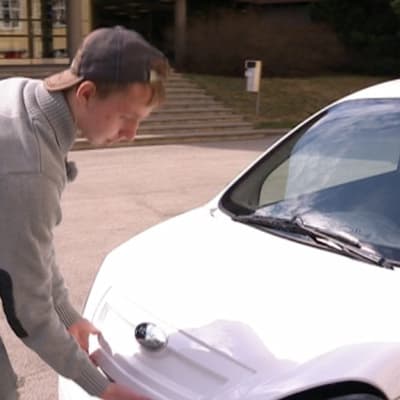 Vester Saarinen avaa mopoautonsa konepeltiä.